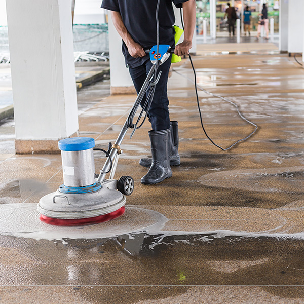 professional in black uniform cleaning concrete with pressure washer